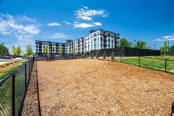 a fenced in dog park with apartments in the background